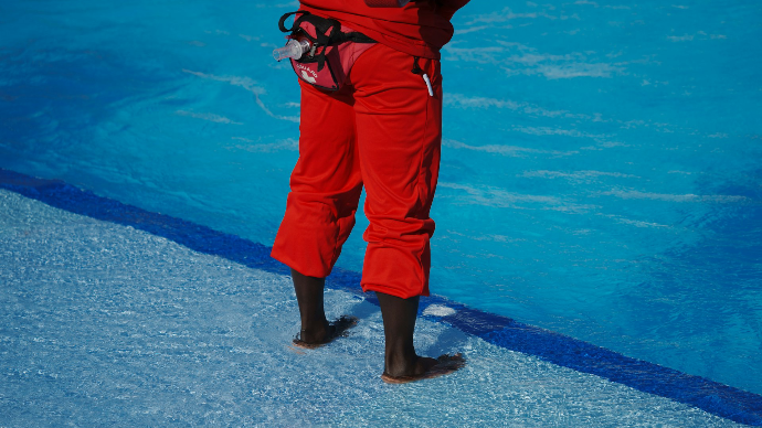 A person in a red snow suit holding a snowboard